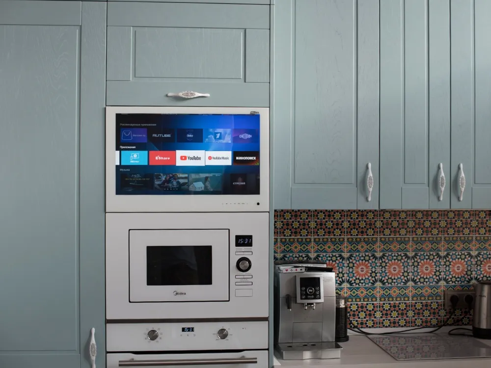 AVEL TV in a light blue kitchen cabinet above the microwave and oven