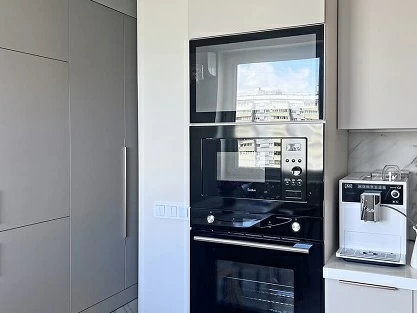 AVEL TV above a built-in oven in a grey kitchen
