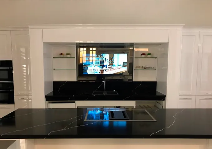 Custom AVEL TV in a white wall niche above a black countertop