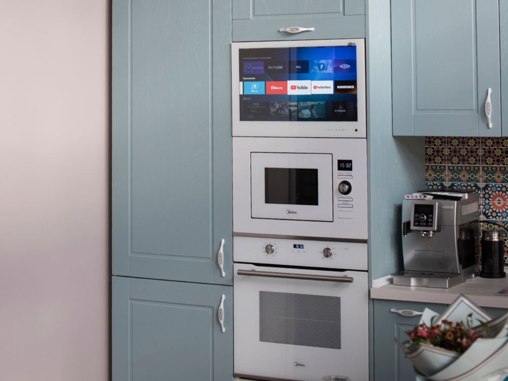 AVEL TV in a light blue kitchen cabinet above the microwave and oven