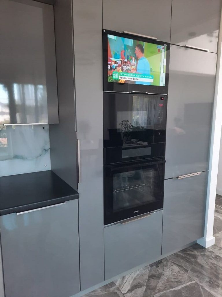 AVEL TV above the ovens in a grey glossy kitchen