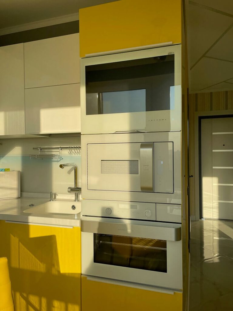 AVEL TV in a yellow and white kitchen above built-in appliances