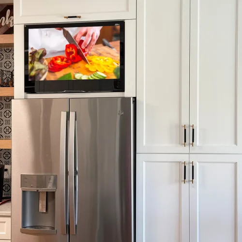 AVEL AVS325KS TV above a refrigerator in a white kitchen