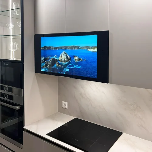 AVEL TV built into a grey kitchen wall cabinet above the cooktop