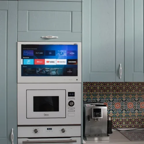 AVEL TV in a light blue kitchen cabinet above the microwave and oven